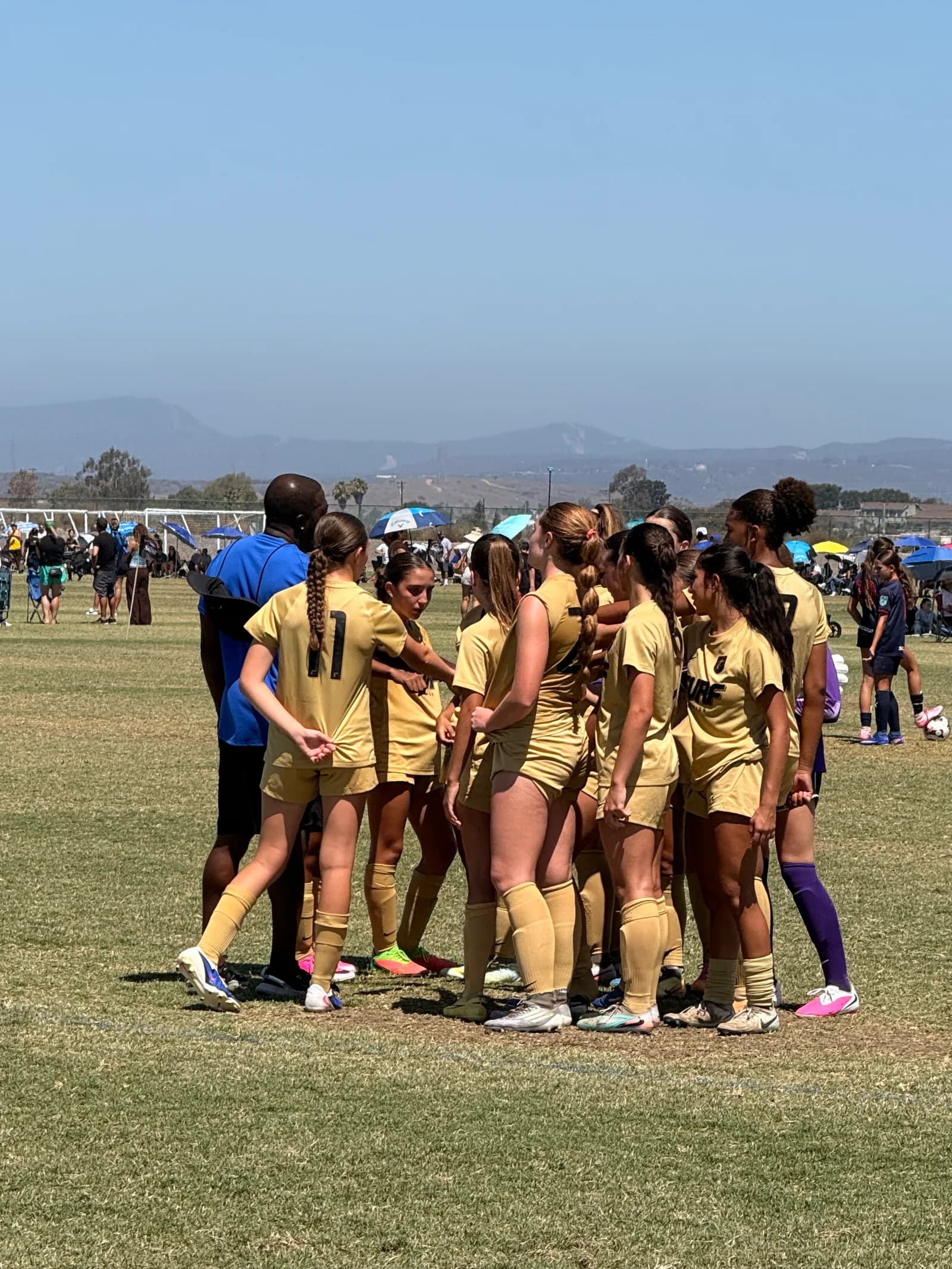 South Valley Surf girls in gold jerseys huddled with their coach on match day